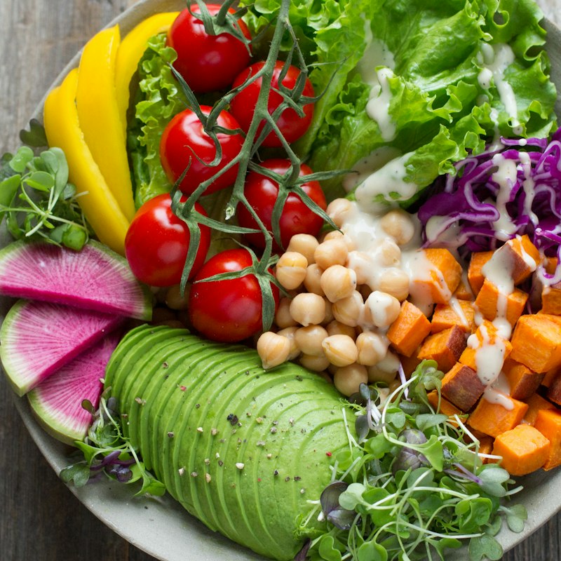 Bord met avocado, kikkererwten, zoete aardappel en cherrytomaten