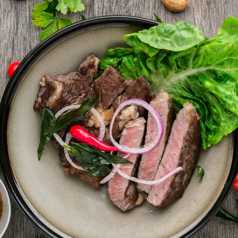 Bord met gesneden bavette, rode ui, chili en sla